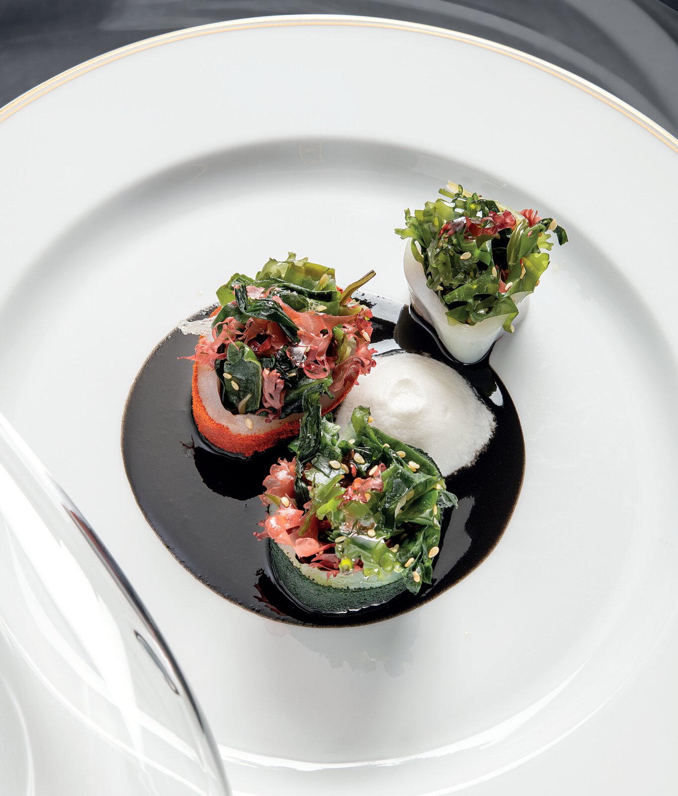 Chipirons farcis aux parties crémeuses de tourteau, salade d’algues aux graines de sésame, sauce à l’encre et espuma coco