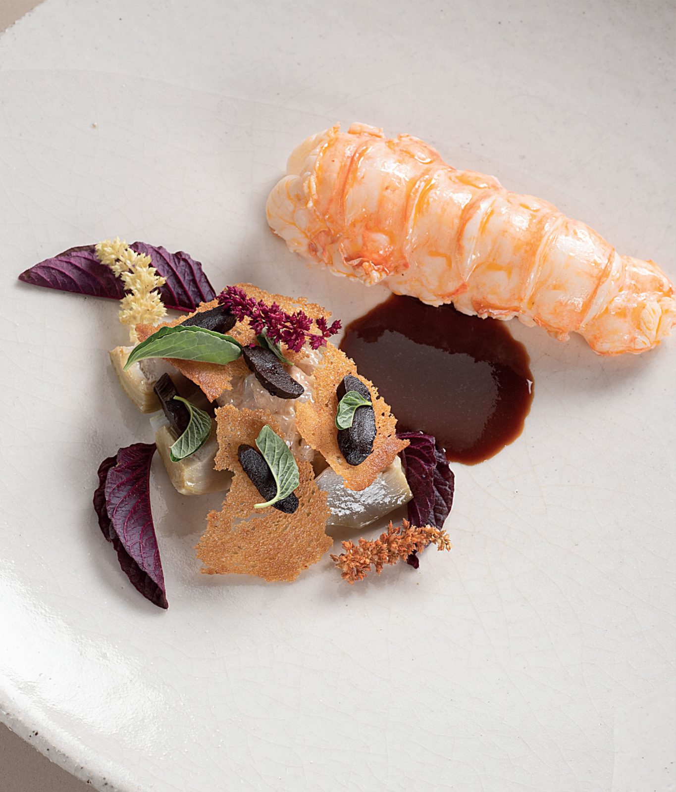 Langoustine pochée, artichaut poivrade et ail noir, jus de carcasses au poivre rouge cacao
